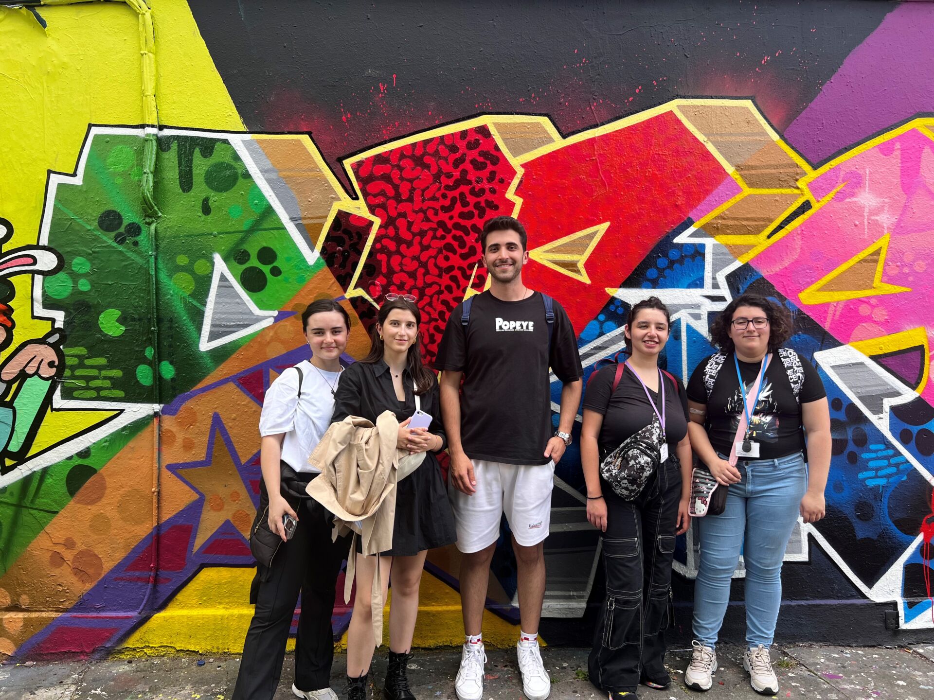 KAE students posing in front of graffiti