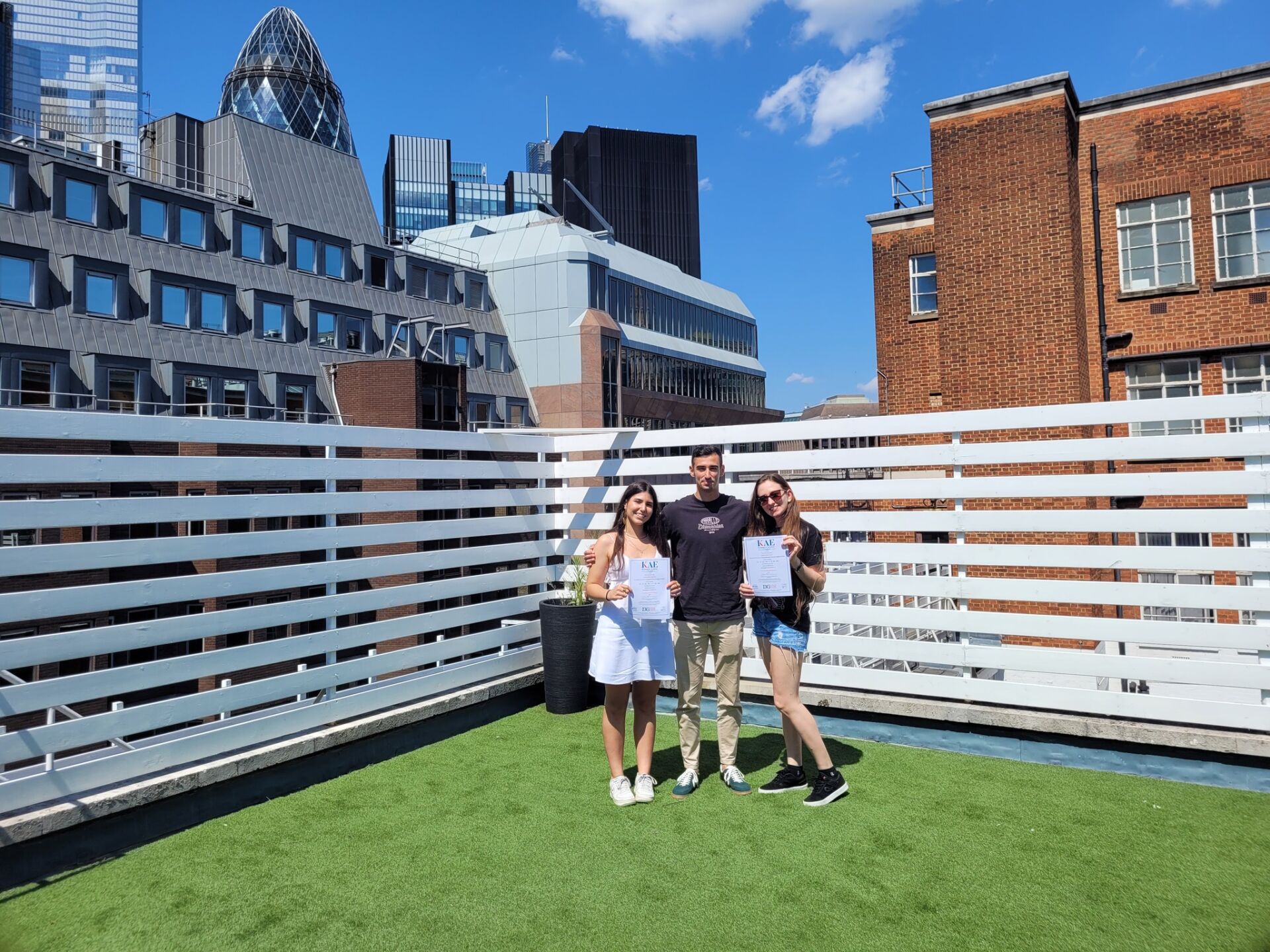 KAE students finishing their English course posing for photos on the KAE rooftop garden with the Gherkin in the background